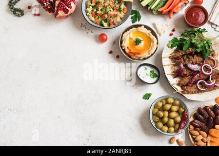 Arabische und Orientalische Küche, Tisch. Fleisch Kebab, Hummus, tabbouleh Salat, Saucen, Oliven, Pita, Termine Früchte, Nüsse, Granatapfel. Stockfoto