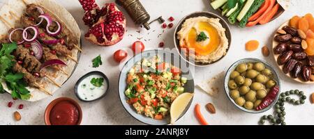 Arabische und Orientalische Küche, Tisch. Fleisch Kebab, Hummus, tabbouleh Salat, Saucen, Oliven, Pita, Termine Früchte, Nüsse, Granatapfel. Stockfoto