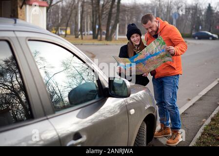 Karte in den Händen der jungen Menschen auf der Straße mit einem Auto. Stockfoto