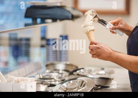 Arbeitnehmer setzt italienisches Eis in Horn mit Schokolade Stockfoto