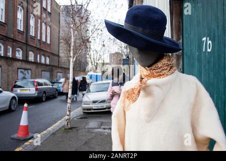 LONDON - Dezember 20, 2020, eine Schaufensterpuppe in einem weißen Strickjacke, ein gelbes Halstuch und einem blauen Hut mit breiter Krempe steht auf der Straße in der Nähe ein Geschäft mit einem Stockfoto