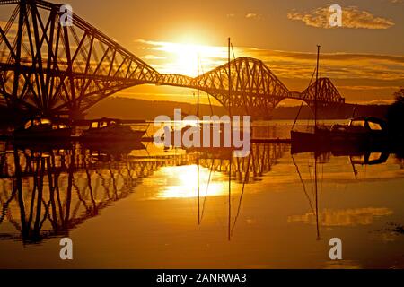 North Queensferry, Schottland, Großbritannien. Januar 2020. Kurz nach Sonnenaufgang, mit Blick auf die Forth Estuary in Richtung Edinburgh zu einer Silhouette der Forth Rail Bridge und kleiner Fischerboote Stockfoto