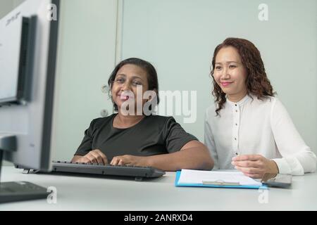 Zwei Geschäftsfrauen oder Unternehmensfachleute arbeiten zusammen und in einer Diskussion. Bürotisch mit Computer. Stockfoto