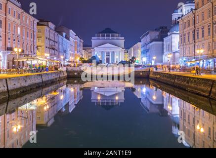 Triest - Dezember 2016, Italien: Nächtlicher Blick auf den Canal Grande in der Stadt Triest, alte Kirche und historische Gebäude spiegeln sich im Wasser wider Stockfoto