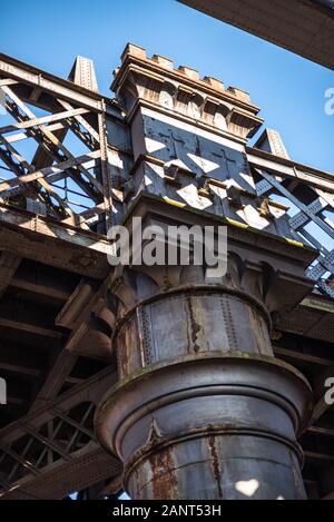 Dunkle und düstere Industrieatmosphäre unter den historischen Bahnbrücken in Manchester U-Bahn-Symmetrie Sonnenstrahlen Tag blauer Himmel Stockfoto