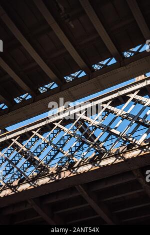 Dunkle und düstere Industrieatmosphäre unter den historischen Bahnbrücken in Manchester U-Bahn-Symmetrie Sonnenstrahlen Tag blauer Himmel Stockfoto