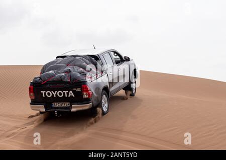 toyota hulux revo klettert eine Sanddüne, die Sand in einer Dasht e lut- oder sahara-Wüste umspritzt Stockfoto