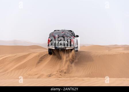 toyota hulux revo klettert eine Sanddüne, die Sand in einer Dasht e lut- oder sahara-Wüste umspritzt Stockfoto