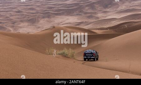 toyota hulux revo klettert bei regnerischem Wetter in der Dasht e lut- oder sahara-Wüste eine Sanddüne hinab Stockfoto