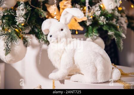 Weißer künstlicher Kaninchen Hasen auf dem Hintergrund der Weihnachtsbaum Stockfoto