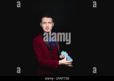 Illusionist zeigt Fokus mit Spielkarten in den Händen auf schwarzem Hintergrund Stockfoto