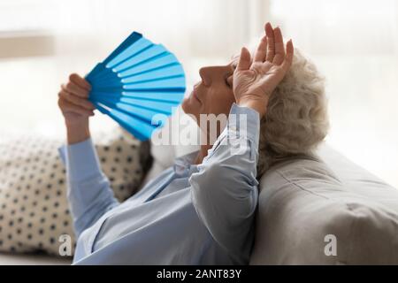 Ältere erschöpft Frau Unwohlsein, leiden unter Hitze, winken Ventilator Stockfoto