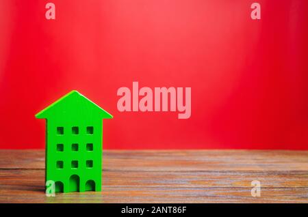 Miniatur Holz- Haus auf einem roten Hintergrund. Sweet Home Konzept. Kauf und Verkauf von Immobilien. Bezahlbare Wohnungen für junge Familien. Apartments für Stockfoto