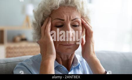 Close up unglücklich ältere Frau Tempel berühren, leiden unter Kopfschmerzen. Stockfoto