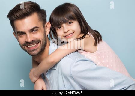 Glückliche junge Papa Holding wenig Vorschule lächelnden Tochter auf der Rückseite. Stockfoto