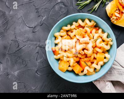 Fusilli mit Kürbis, Rosmarin und Brie Käse. Idee Rezept Pasta. Vegetarisches Essen. Hausgemachte Pasta Teller in blau Schüssel über Schwarze konkreten Hintergrund. Kopieren Sie Platz. Top View oder flach. Stockfoto