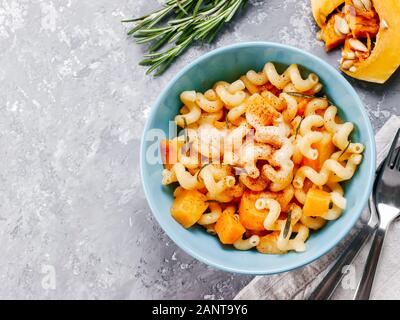 Fusilli mit Kürbis, Rosmarin und Brie Käse. Idee Rezept Pasta. Vegetarisches Essen. Hausgemachte Pasta Teller in blau Schüssel über grauer Beton Hintergrund. Kopieren Sie Platz. Top View oder flach. Stockfoto