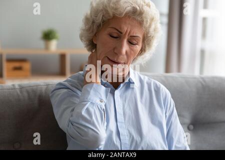 Unglücklich ältere Frau massieren verspannte Nackenmuskulatur, Unwohlsein Stockfoto