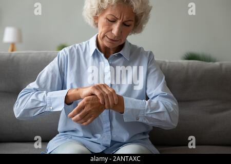 Unglücklich ältere Frau zu massieren, Handgelenk, Gefühl, Schmerz in gemeinsamen Stockfoto