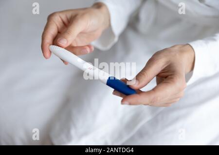 Schließen Sie die junge Frau mit der Schwangerschaft Test in den Händen Stockfoto
