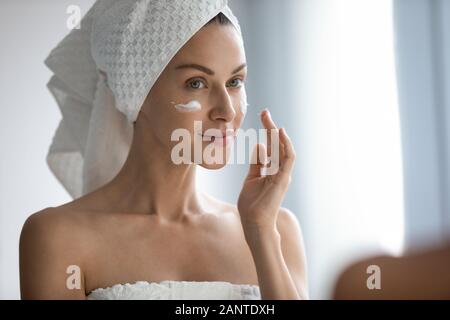 Nahaufnahme, schöne Frau, die Sahne, im Spiegel zu betrachten Stockfoto