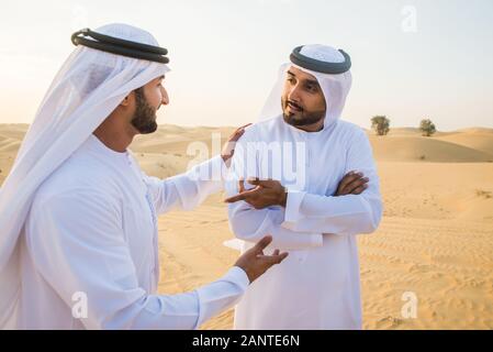 Arabische Männer witk kandora Wandern in der Wüste - Porträt von zwei mittleren Osten Erwachsene mit traditionellen arabischen Kleid Stockfoto