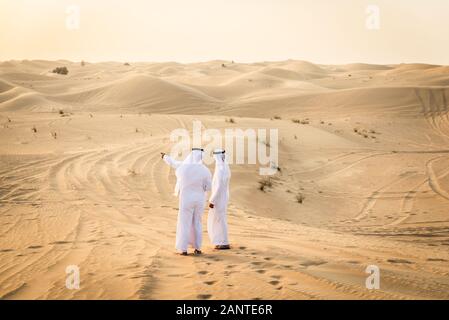 Arabische Männer witk kandora Wandern in der Wüste - Porträt von zwei mittleren Osten Erwachsene mit traditionellen arabischen Kleid Stockfoto