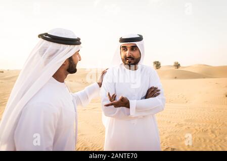 Arabische Männer witk kandora Wandern in der Wüste - Porträt von zwei mittleren Osten Erwachsene mit traditionellen arabischen Kleid Stockfoto