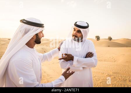 Arabische Männer witk kandora Wandern in der Wüste - Porträt von zwei mittleren Osten Erwachsene mit traditionellen arabischen Kleid Stockfoto