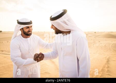 Arabische Männer witk kandora Wandern in der Wüste - Porträt von zwei mittleren Osten Erwachsene mit traditionellen arabischen Kleid Stockfoto