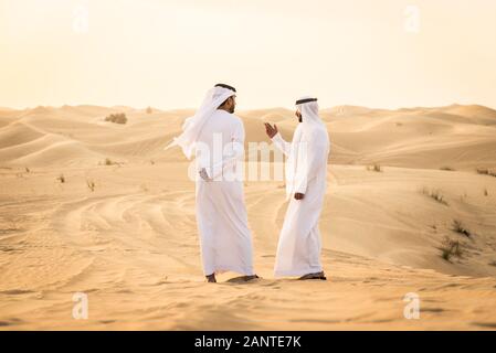 Arabische Männer witk kandora Wandern in der Wüste - Porträt von zwei mittleren Osten Erwachsene mit traditionellen arabischen Kleid Stockfoto