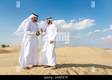 Arabische Männer witk kandora Wandern in der Wüste - Porträt von zwei mittleren Osten Erwachsene mit traditionellen arabischen Kleid Stockfoto