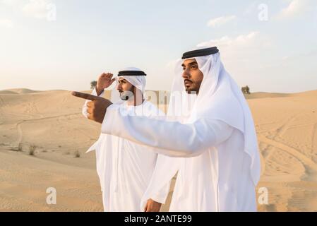 Arabische Männer witk kandora Wandern in der Wüste - Porträt von zwei mittleren Osten Erwachsene mit traditionellen arabischen Kleid Stockfoto