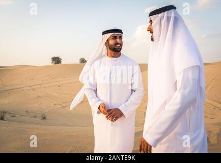 Arabische Männer witk kandora Wandern in der Wüste - Porträt von zwei mittleren Osten Erwachsene mit traditionellen arabischen Kleid Stockfoto