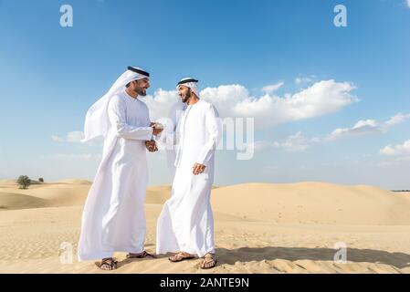 Arabische Männer witk kandora Wandern in der Wüste - Porträt von zwei mittleren Osten Erwachsene mit traditionellen arabischen Kleid Stockfoto