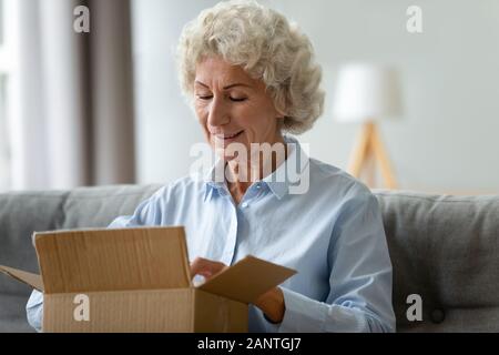 Lächelnde ältere Frau auspacken Karton, hat Paket Nahaufnahme Stockfoto