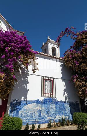 Blühende Bäume und altes Gemälde auf Azulejos an der Igreja de Santa Luzia Kirche in Lissabon, Portugal, an einem sonnigen Tag. Stockfoto