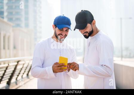Mitte - östliche junge Erwachsene tragen kandora Walking im Freien in Dubai - Arabische Emirate Mann die traditionelle Kleidung Stockfoto