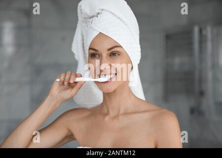 Schöne Frau mit Handtuch auf dem Kopf Zähne putzen Stockfoto