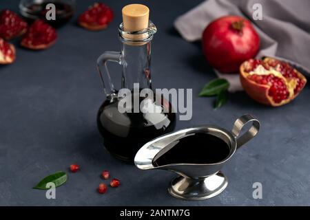 Granatapfel Soße in eine Flasche und Soße Boot mit Körnern und Stücke des Granatapfels auf einem dunklen Hintergrund. Seitenansicht, selektiven Fokus. Stockfoto