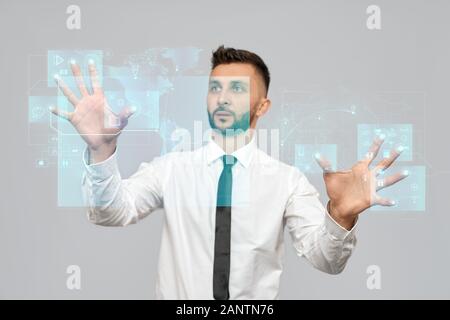Porträt des jungen Geschäftsmannes im Hemd im Büro. Selektiver Fokus der digitalen taktilen Karten Bildschirm, bärtiger Mann berührt virtuelle Symbole auf der Projektion. Konzept der Hochtechnologien, Digitalisierung. Stockfoto