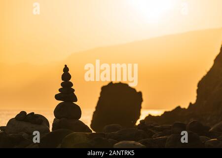 Haufen Steine in der Nähe von Meer bei Sonnenaufgang. Ribeira da Janela, Madeira Stockfoto