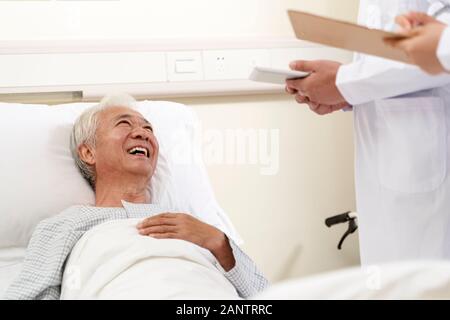 Gerne asiatische alten Mann liegen im Krankenhausbett im Gespräch mit Ärzten Stockfoto