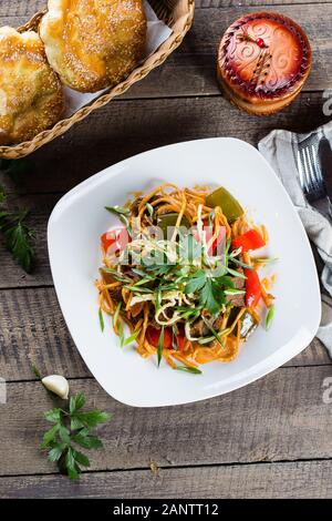 Traditionelle asiatische usbekischen Nudel lagman mit Gemüse und Fleisch auf rustikalen Holztisch Hintergrund. Ansicht von oben Stockfoto