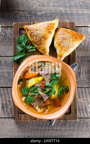 Asiatische Suppe shurpa mit Fleisch und Gemüse in der Platte auf wooned Tabelle. Ansicht von oben Stockfoto