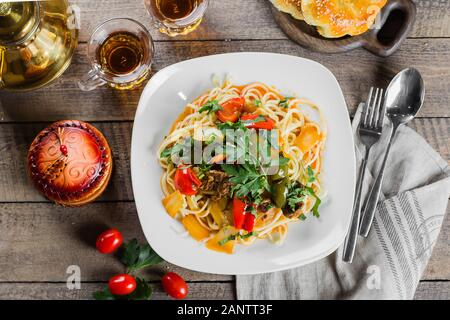 Traditionelle asiatische usbekischen Nudel lagman mit Gemüse und Fleisch auf rustikalen Holztisch Hintergrund. Ansicht von oben Stockfoto