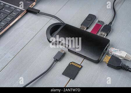 USB Typ-C-Adapter oder Hub in den Laptop mit verschiedenen Accessoires - Pendrives, HDMI, Ethernet, Speicherkarte, Kabel verbunden. Stockfoto