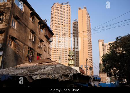 Neue Hochhäuser, die über eine Moschee und ein älteres, halbverderbtes Gebäude im überlasteten Bhendi Bazare Gebiet, Mumbai (Bombay), Indien, ragen Stockfoto