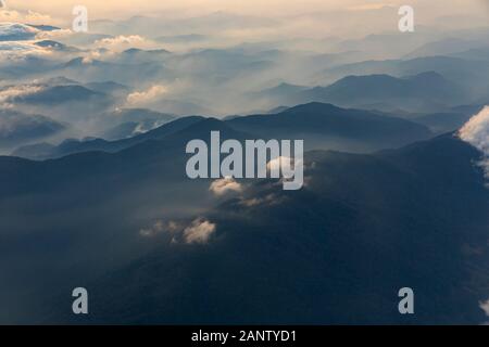 Fliegen Sie im Morgengrauen in der Nähe der Stadt da Lat über das zentrale Hochland Vietnams. Wolken und Nebel enthüllen die darunterliegenden hohen Berge Stockfoto