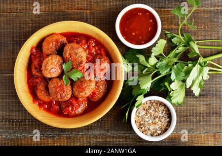 Lecker Frikadellen in Tomatensoße in Houten, Tomatensauce und frischer Petersilie. Ansicht von oben, flach Stockfoto